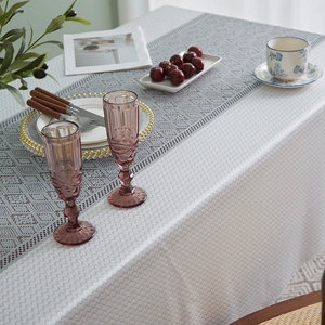 Detail of white cotton linen tablecloth with a grey geometric hollow lace runner