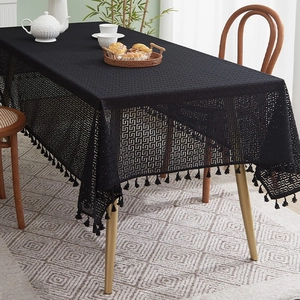 Detailed close-up of black lace hollowed tablecloth with geometric patterns and tassels