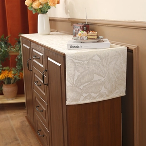 Elegant light beige table runner with leaf jacquard pattern on dark wooden cabinet