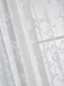 Close-up of white lace curtain featuring intricate floral embroidery and semi-transparent mesh