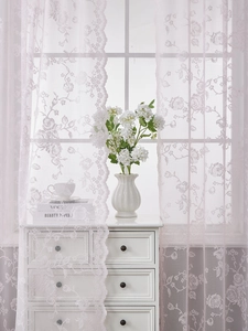 Detail of pink French lace curtain featuring rose floral patterns and wavy scalloped edges