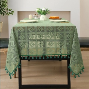 Detail of green hollow woven tablecloth featuring diamond patterns and elegant fringe