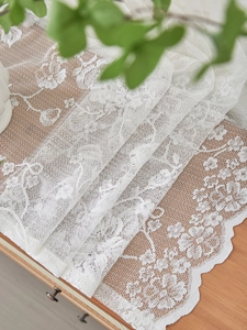 Close-up of white floral mesh lace curtain with elegant scalloped edges on wooden cabinet