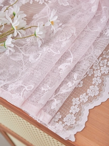 Detailed view of pink floral lace fabric with scalloped edges for home decoration