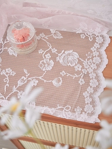 Detail showing white lace fabric with intricate rose flower embroidery and scalloped edges