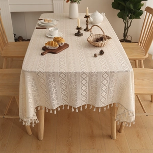 Detail view of beige bohemian lace tablecloth with geometric patterns and fringe
