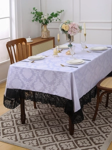 Detailed view of damask pattern tablecloth with black lace edge and elegant dinner set