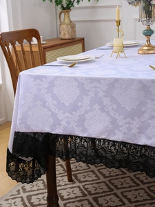 Detail of vintage white tablecloth featuring damask jacquard and black lace borders