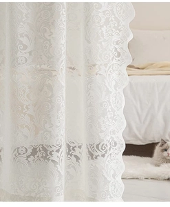 Dettaglio della tenda in pizzo bianco con motivo floreale e bordi smerlati eleganti