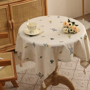 Linen round tablecloth with floral embroidery and cream tassel fringe in warm setting