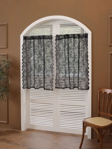 Detail of black lace cafe curtains featuring floral patterns and elegant wavy edges