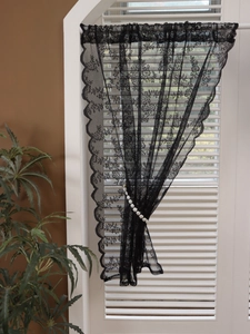 Close-up of black floral lace curtain featuring delicate embroidery and wavy scalloped edges