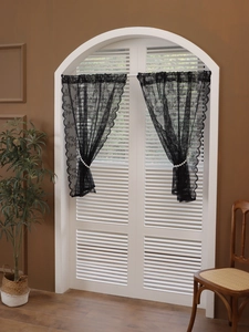 Detail of black lace curtain with floral mesh pattern and scalloped edges for home decor