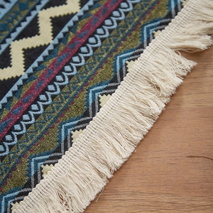 Close-up of bohemian woven tablecloth with vibrant geometric patterns and cream tassels