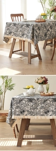 Detail of jacquard tablecloth featuring black palm trees, jungle animals and fringe edges