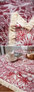 Detail of red floral jacquard fabric with cream tassels showing texture and vintage pattern