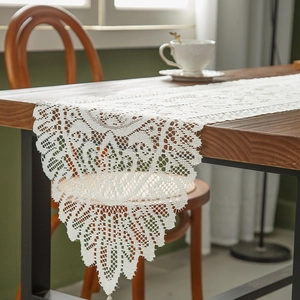 French style white lace table runner with hollow floral pattern and fringe on wooden table