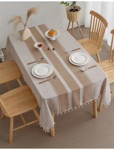 Detail of linen table cloth with beige brown stripes, woven patterns and white tassels