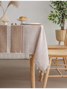 Close-up of linen woven tablecloth with beige and brown stripes and fringe details