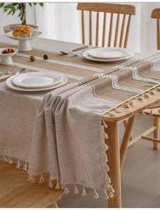 Close-up of linen table runner with lace trim and tassel edge on wooden table