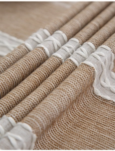 Close-up of linen woven tablecloth showing beige texture and white embroidery details
