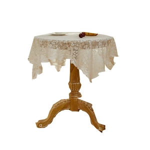 Elegant white lace tablecloth with floral hollow embroidery on a round wooden table