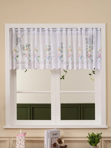 Close-up of white lace curtain featuring colorful floral embroidery and wavy scalloped hem