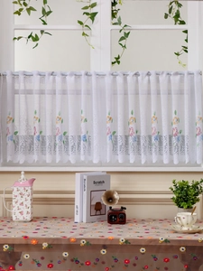 Detail view of white lace cafe curtain with floral embroidery and wavy edges