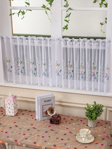 Detail showing white lace cafe curtain with floral embroidery and hollow patterns
