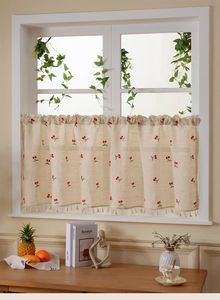 Detail of linen cafe curtain with red cherry embroidery and elegant fringe tassels