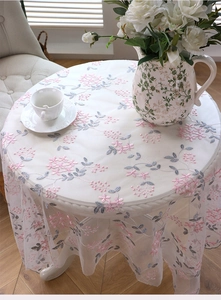 Detail shot of white mesh lace tablecloth with delicate pink and grey floral embroidery