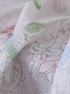 Macro shot of thick white lace door curtain with delicate floral patterns and mesh texture