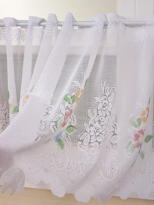 Detail of white lace curtain with colorful floral embroidery and wavy scalloped edge