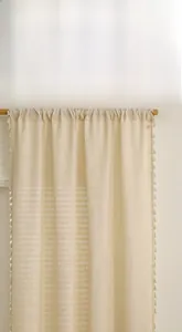 Close-up of beige linen curtain fabric featuring detailed weave texture and tassel edge
