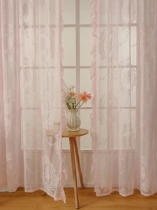 Detail of pink French lace curtain with floral embroidery and elegant ruffled edges
