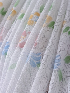 Close-up of thick white lace fabric featuring pastel floral prints and mesh texture