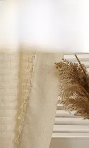 Detailed close-up of beige linen curtain fabric featuring elegant small decorative tassels