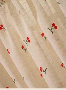 Macro detail of cherry embroidery on beige linen texture fabric with light filtering