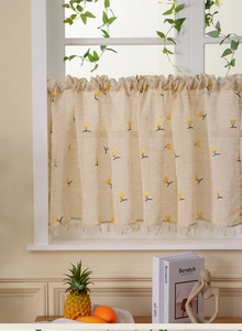 Detailed embroidery of yellow cherries on a beige linen cafe curtain with fringe trim