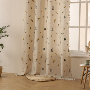 Tende in lino beige con motivi floreali e nappe per l'arredamento della camera