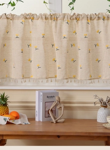 Detailed texture of beige linen cafe curtain with yellow floral embroidery and tassel fringe