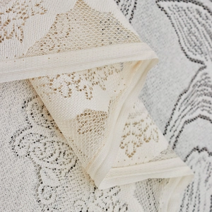 Close-up of cream lace picnic mat featuring hollow floral patterns and mesh texture