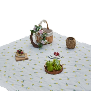 Blue-gray outdoor picnic mat with yellow lemon embroidery and fringe trim on the edge