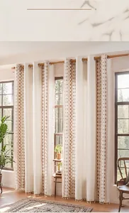 Detailed view of linen curtain with geometric embroidery, metal rings, and white tassels