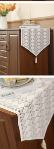 Detail of white lace table runner with geometric triangles and elegant tassels