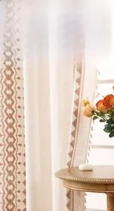 Close-up of linen curtain fabric with geometric embroidery and elegant tassel details