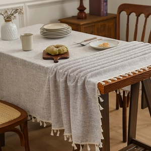 Linen textured tablecloth with cream tassels on a rustic dark wood dining table setup