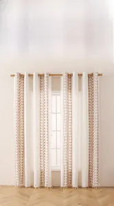 Detail of bohemian curtain with brown geometric embroidery and handmade fringe tassels