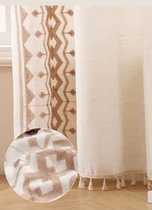 Detail view of beige linen curtain with geometric embroidery and tassel lace trim