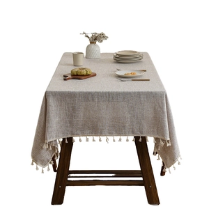 Linen rectangle tablecloth with off-white tassel edges on a wooden dining table